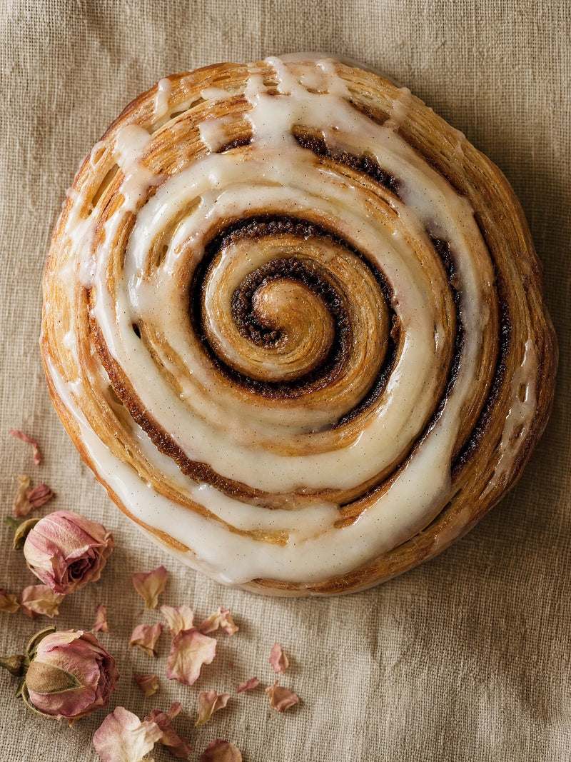 The Single — one soft glazed Merlen Bakehouse cinnamon roll with rose petals